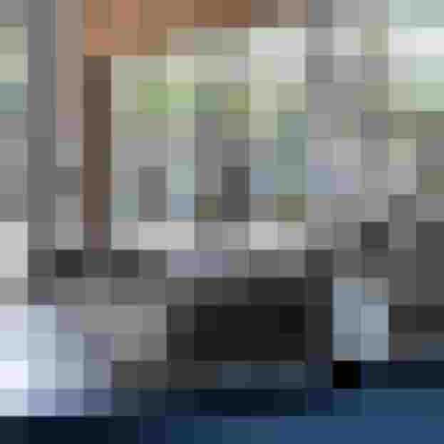 Modernes Loft-Interieur mit Ziegelwand, Glasabtrennung und grauem Sofa