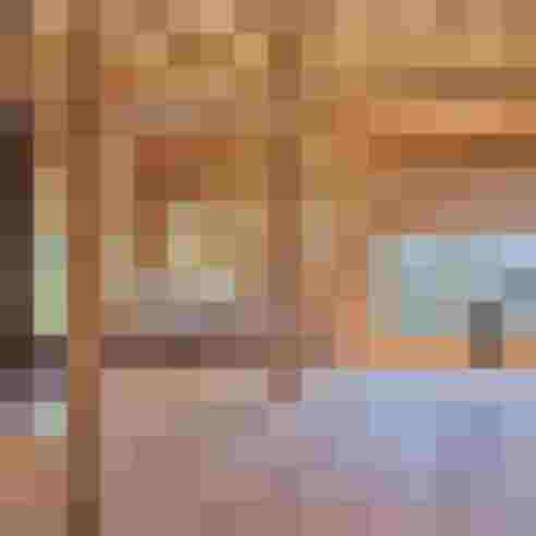 Großer lichtdurchfluteter Innenraum mit sichtbarem Holztragwerk und modernem Ofen